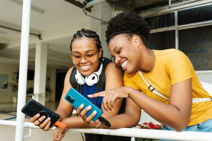 Two smiling women looking at a smartphone together.