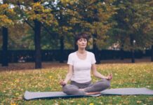 집에서도 손쉽게, ‘마음챙김 운동’ 바람… 실생활 루틴으로 스트레스 줄이기 Woman meditating in a park during autumn.